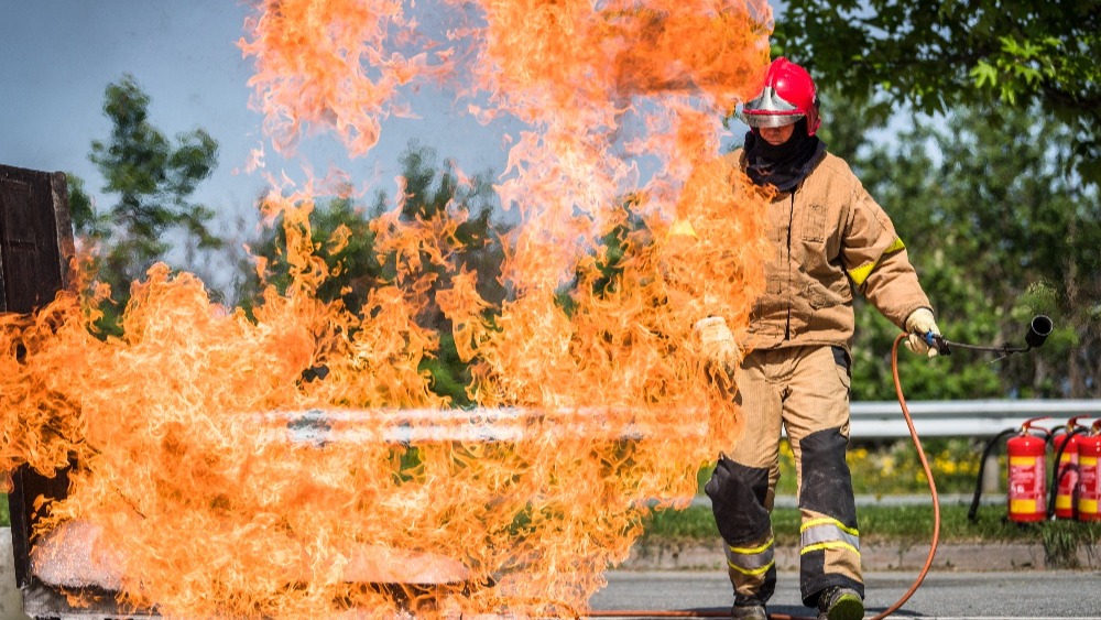 Mann som slokker en brann under en øvelse med et håndholdt brannslokningsapparat.